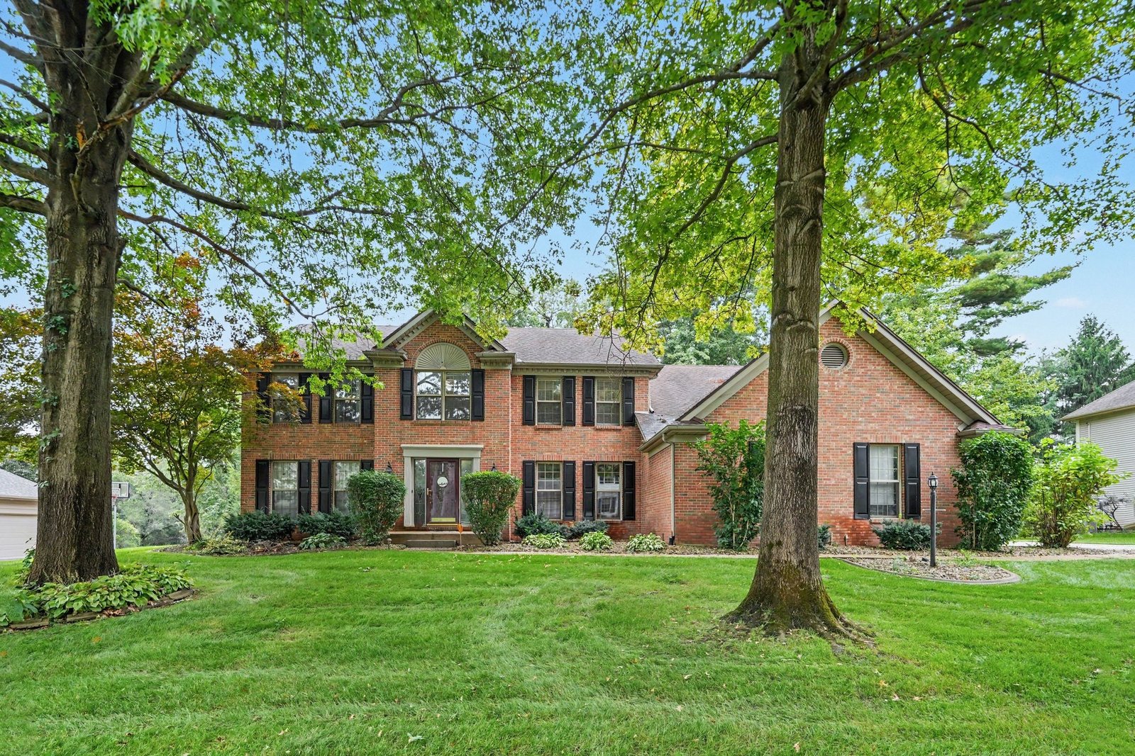 Front exterior of the brick home framed by mature trees